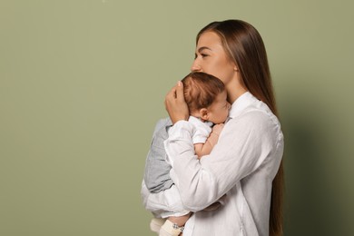 Photo of Mother holding her cute newborn baby on olive background, space for text