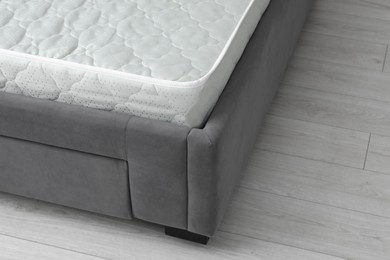Photo of New soft mattress on grey bed indoors, closeup. Space for text