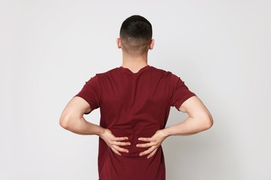 Photo of Man suffering from pain in back on light background. Arthritis symptoms