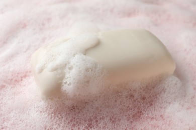 Soap with fluffy foam on pink background, closeup