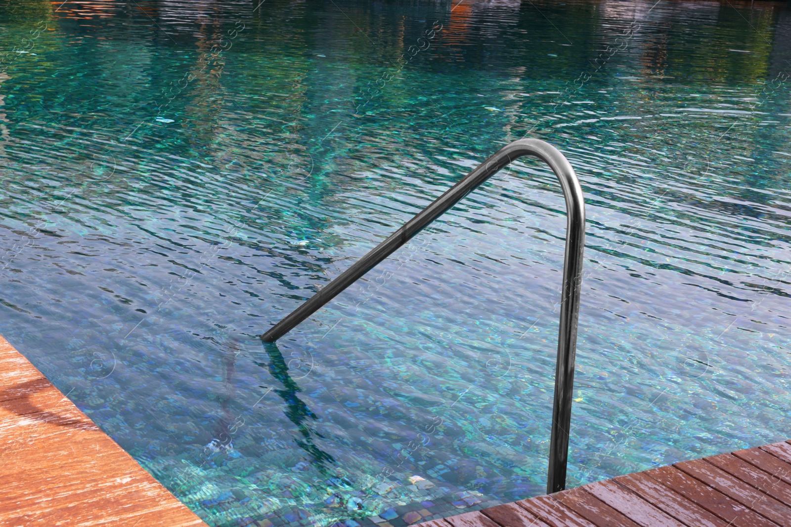 Photo of Swimming pool, metal rail and wooden deck at luxury resort