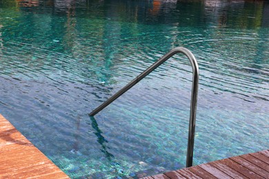 Swimming pool, metal rail and wooden deck at luxury resort