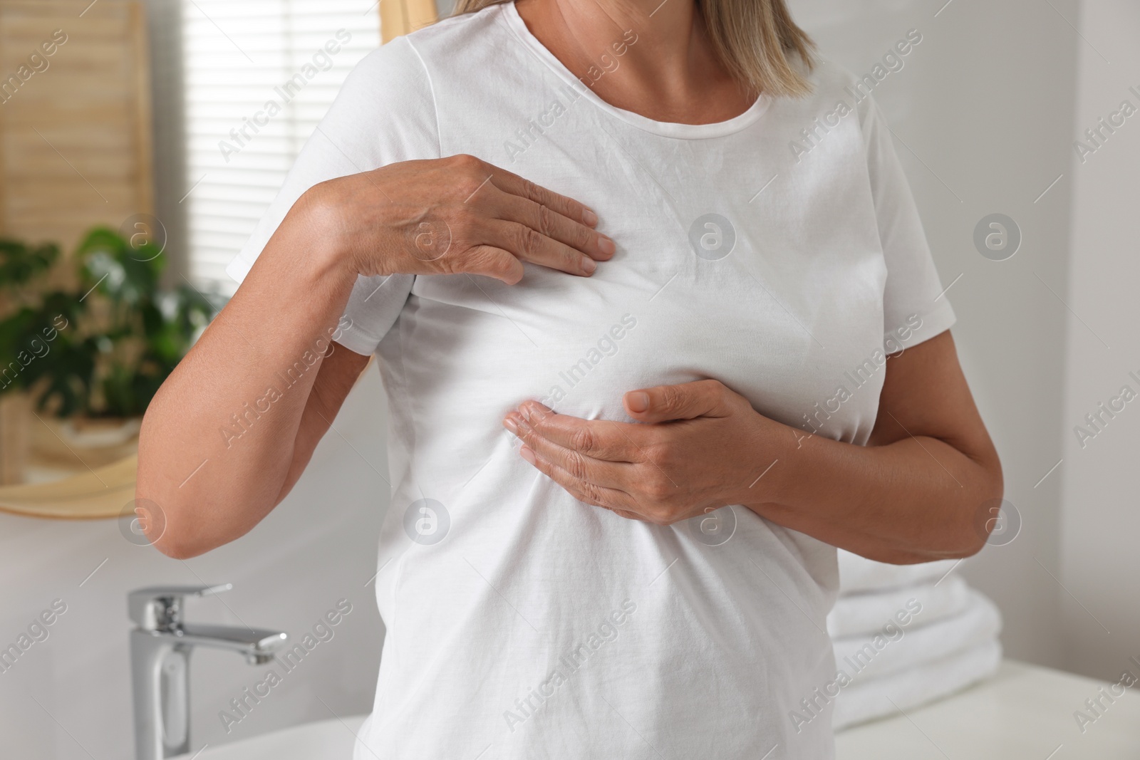 Photo of Woman doing breast self-examination in bathroom, closeup