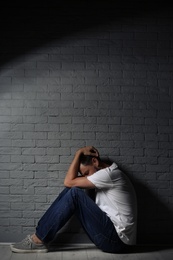 Photo of Lonely man suffering from depression near brick wall