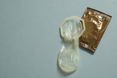 Photo of Unrolled female condom and package on light blue background, above view with space for text. Safe sex