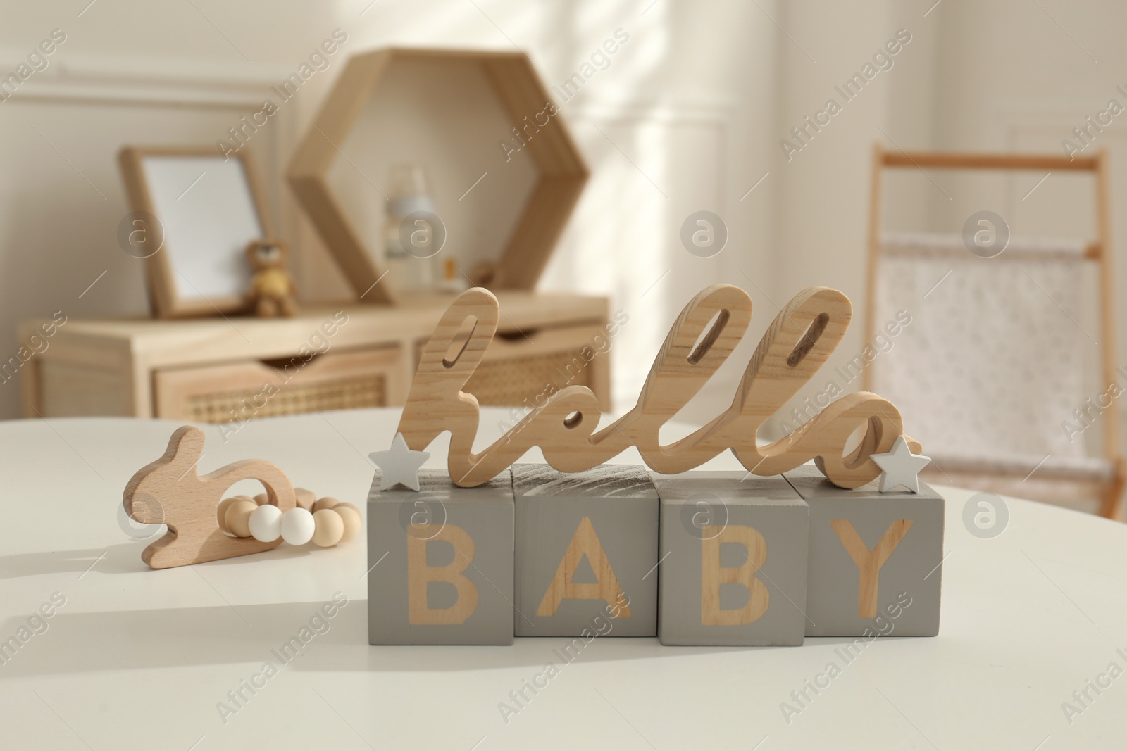 Photo of Decorative phrase Hello Baby on white table in child room. Interior design