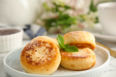 Photo of Delicious cottage cheese pancakes with mint and icing sugar on table, closeup