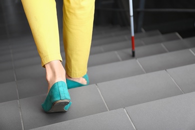 Photo of Blind person going down stairs with long cane, closeup. Space for text