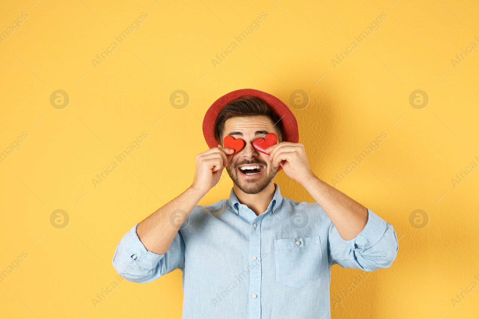 Photo of Man holding decorative hearts on color background