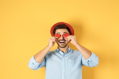 Man holding decorative hearts on color background