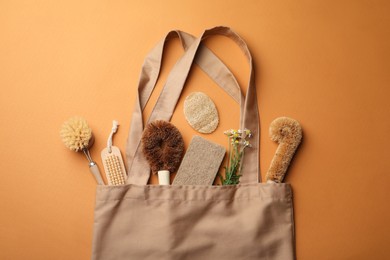 Photo of Bag with eco friendly products on orange background, flat lay. Conscious consumption