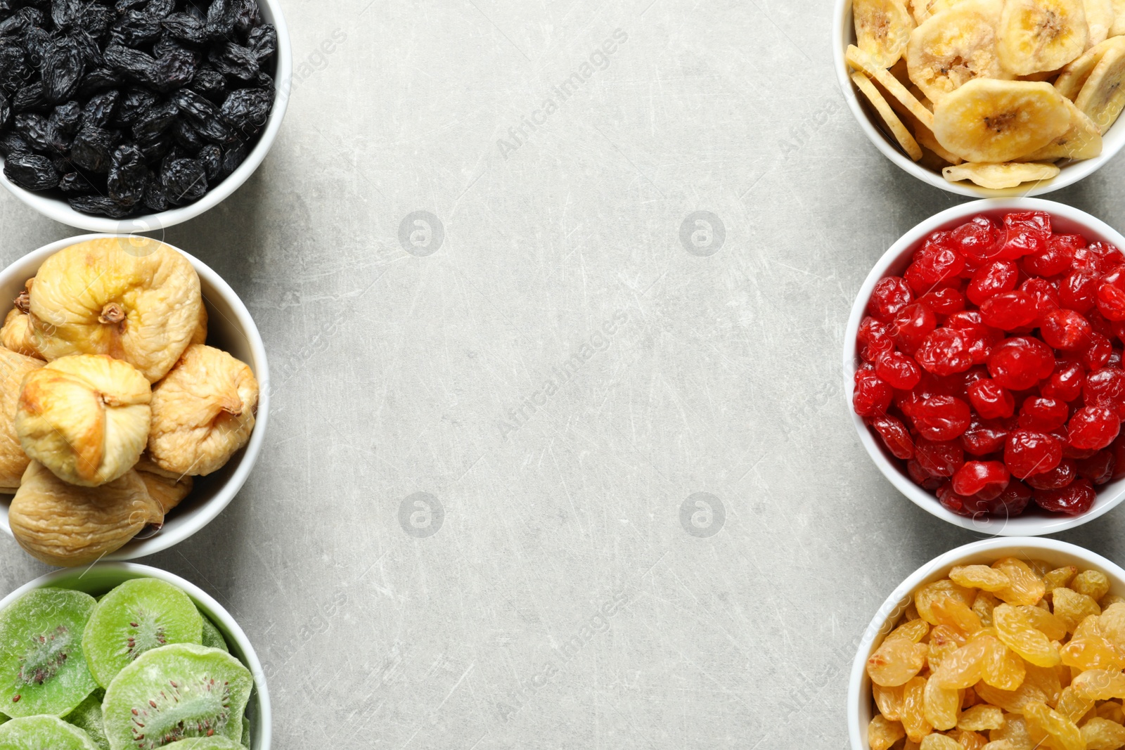 Photo of Bowls of different dried fruits on grey background, top view with space for text. Healthy food