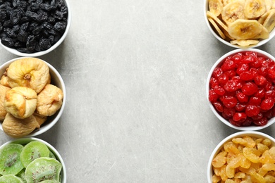 Bowls of different dried fruits on grey background, top view with space for text. Healthy food