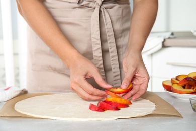 Photo of Woman making peach pie at kitchen table, closeup