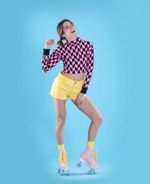 Young woman with retro roller skates on color background