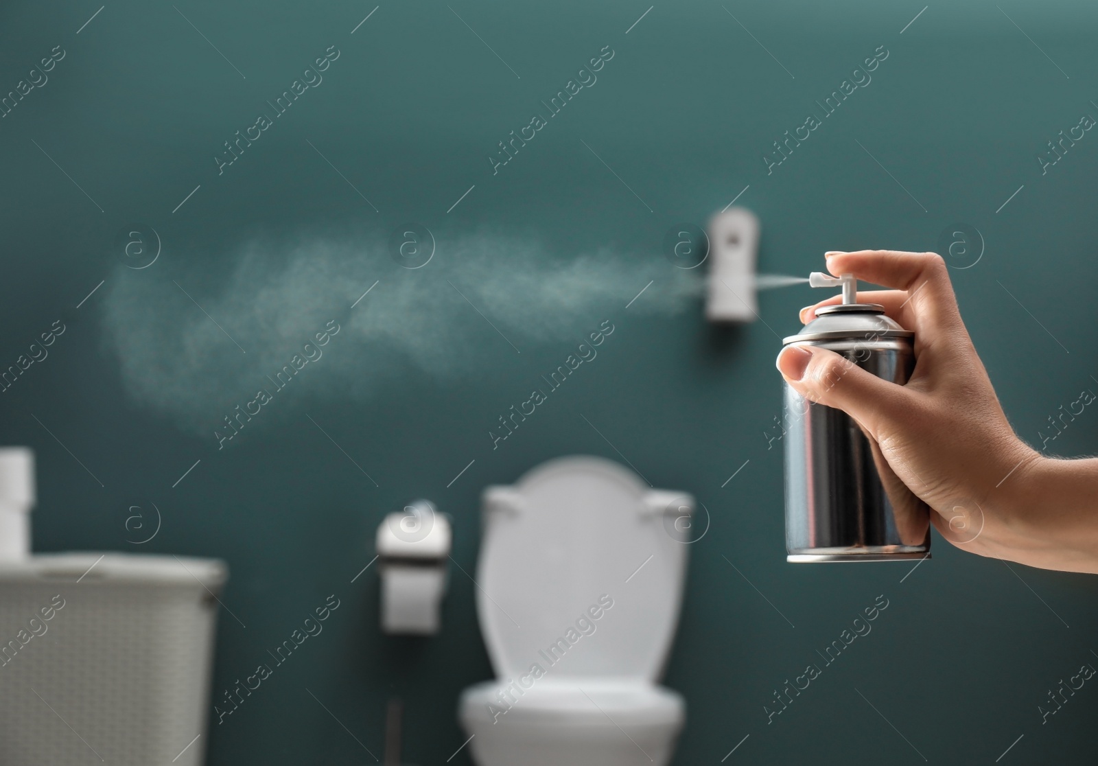 Photo of Woman spraying air freshener in bathroom