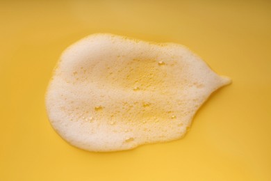 Photo of Sample of fluffy foam on yellow background, top view