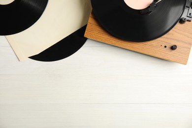 Photo of Vintage vinyl records and turntable on white wooden background, flat lay. Space for text