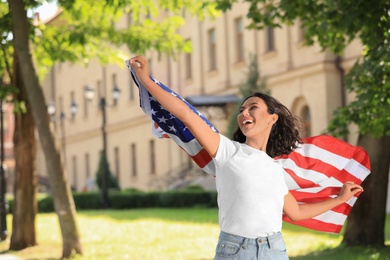 Photo of Happy young woman with American flag on sunny day