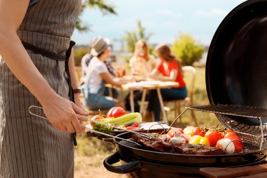 Photo of Man cooking meat and vegetables on barbecue grill outdoors
