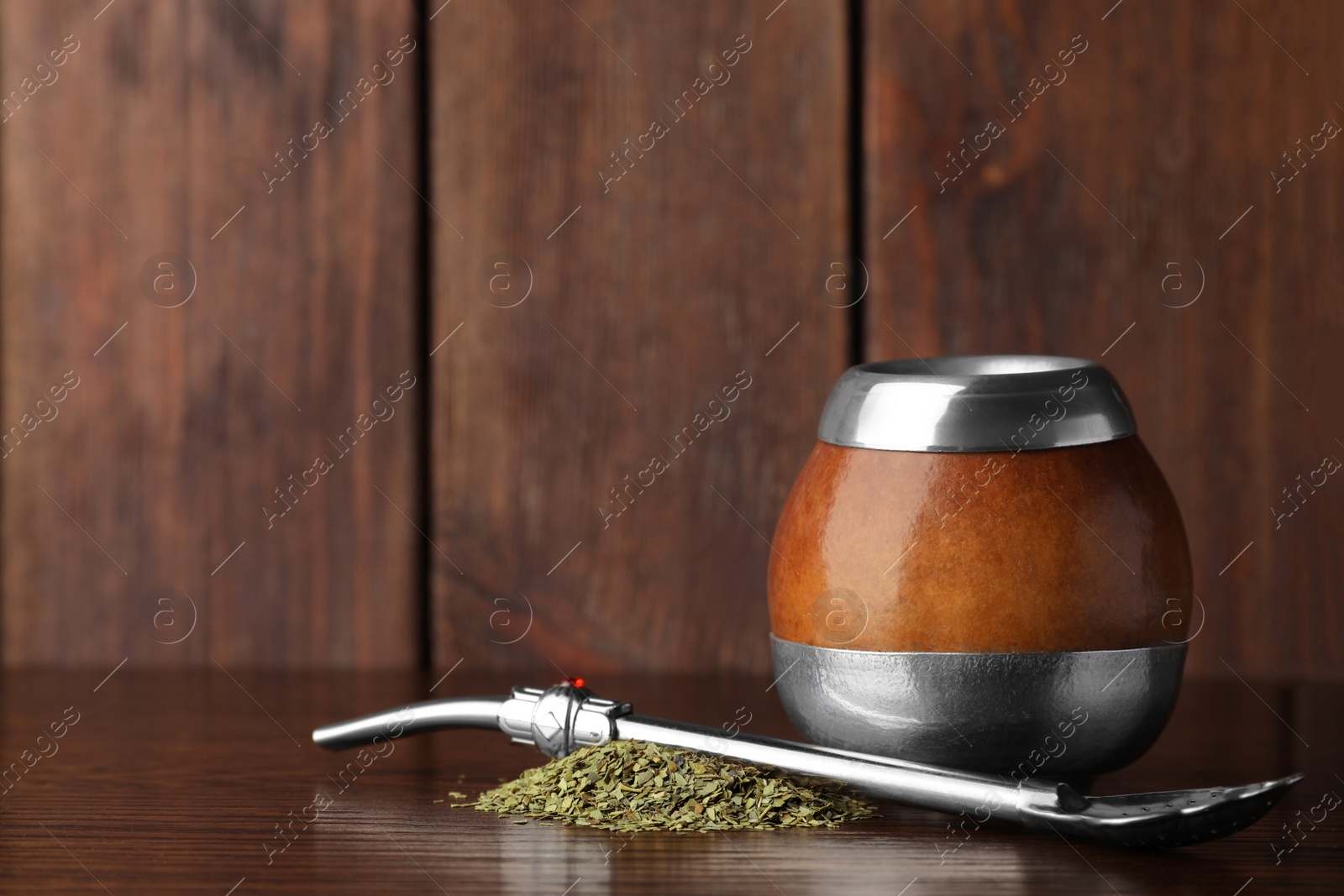 Photo of Calabash with mate tea and bombilla on wooden table. Space for text