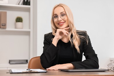 Happy secretary in glasses at table in office