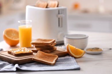 Modern toaster and delicious breakfast on table in kitchen