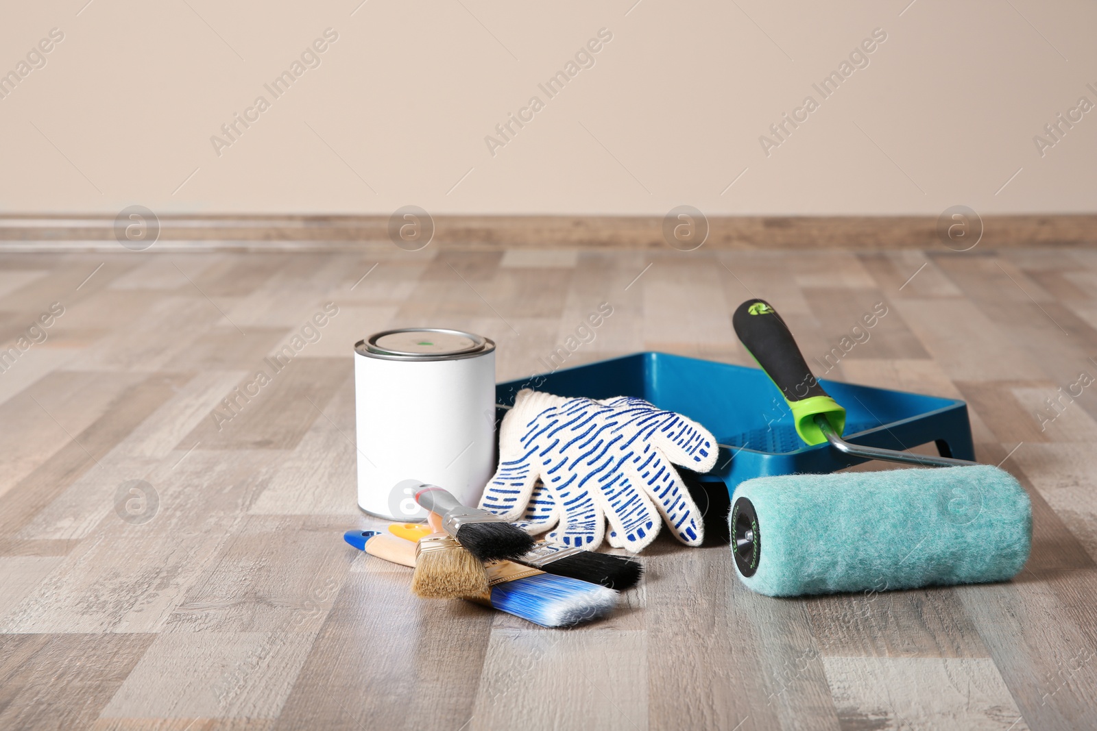 Photo of Can of paint and decorator tools on wooden floor indoors