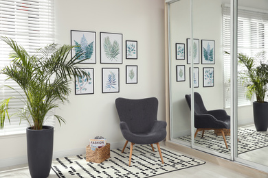 Photo of Beautiful paintings of tropical leaves on white wall in room interior