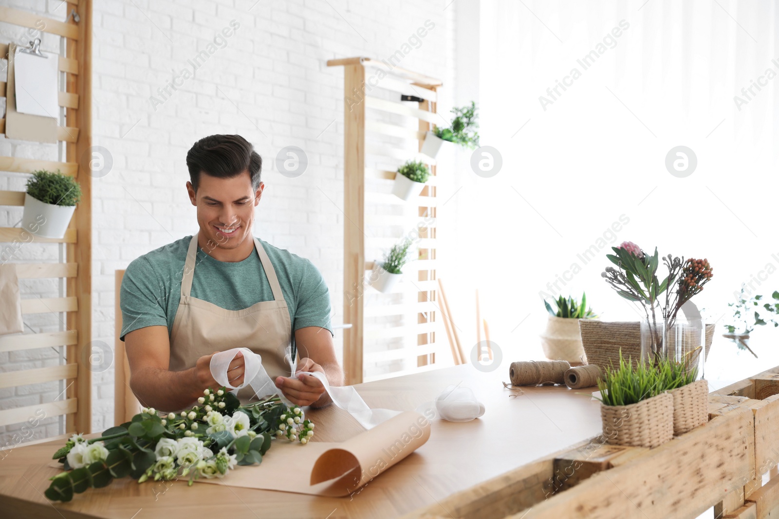 Photo of Florist making beautiful bouquet at table in workshop