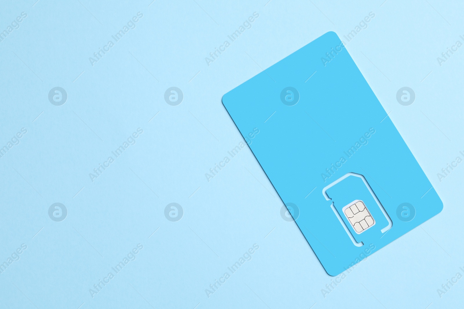 Photo of Modern SIM card on light blue background, top view. Space for text