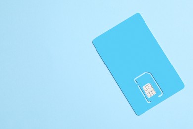 Photo of Modern SIM card on light blue background, top view. Space for text