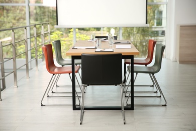 Photo of Modern meeting room interior with large table and projection screen