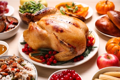 Photo of Traditional Thanksgiving day feast with delicious cooked turkey and other seasonal dishes served on wooden table