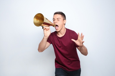 Emotional teenage boy with megaphone on white background