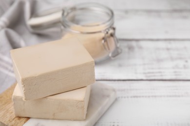 Photo of Blocks of compressed yeast on white wooden table, closeup. Space for text