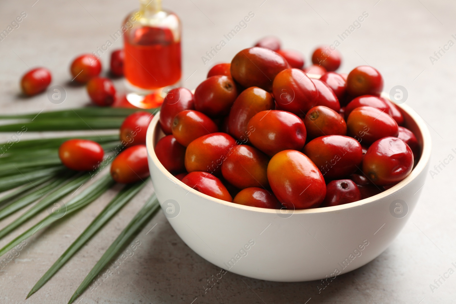 Photo of Palm oil fruits in bowl on grey table, closeup