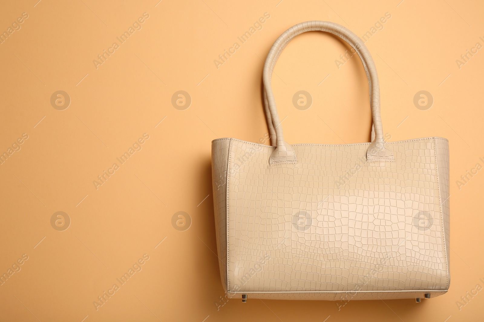 Photo of Stylish women's bag on pale orange background, top view. Space for text