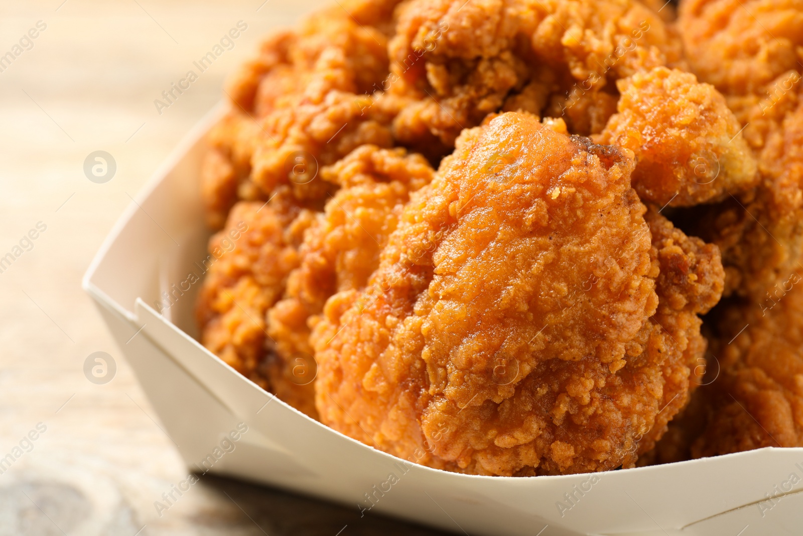 Photo of Tasty deep fried chicken pieces on wooden table, closeup