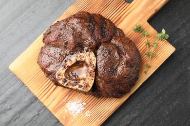 Piece of delicious grilled beef meat, thyme and salt on black table, top view