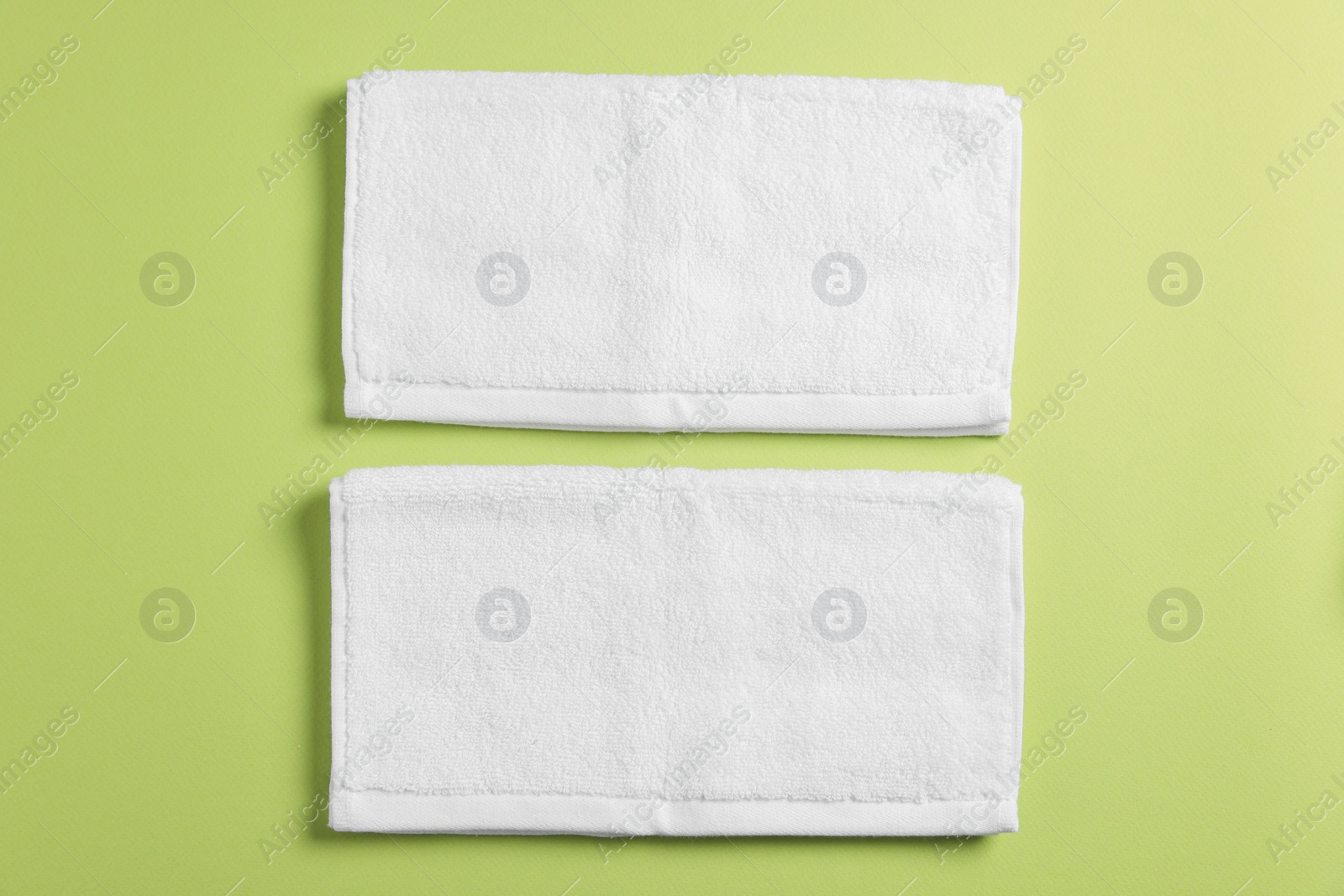 Photo of Soft folded white towels on green background, flat lay