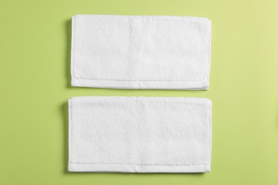 Photo of Soft folded white towels on green background, flat lay