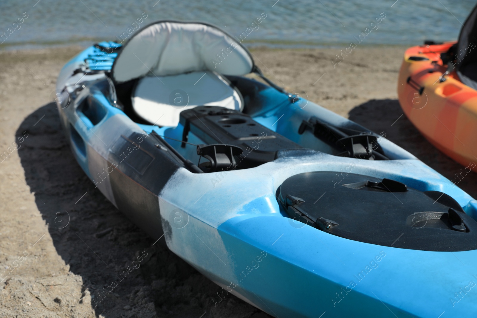 Photo of Bright kayak on sand near river, closeup