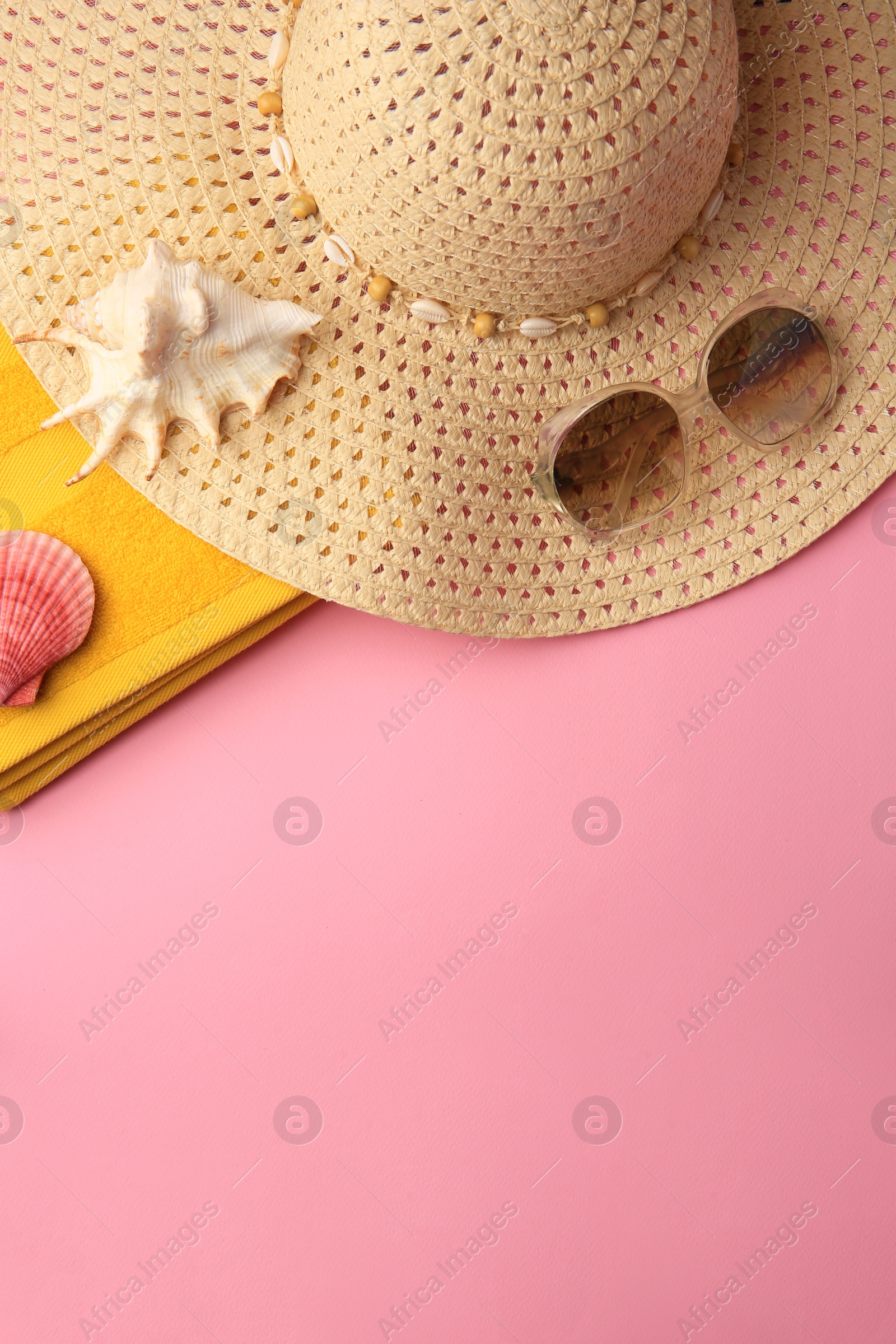 Photo of Sunglasses, hat, towel and shells on pink background, flat lay with space for text. Beach accessories