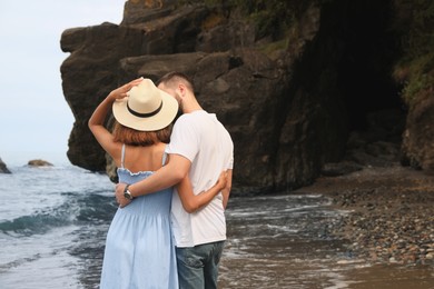 Photo of Young couple on beach near sea, back view. Space for text