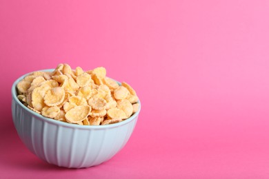 Bowl of tasty crispy corn flakes on pink background, space for text