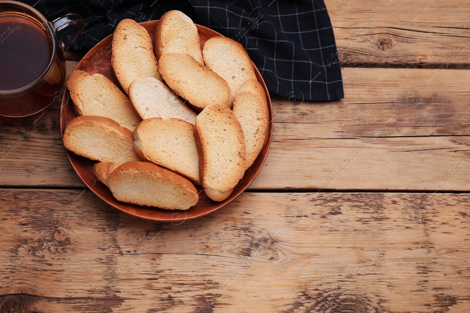 Photo of Hard chuck crackers and cup of tea on wooden table, flat lay. Space for text