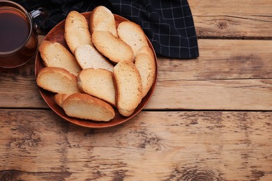 Hard chuck crackers and cup of tea on wooden table, flat lay. Space for text