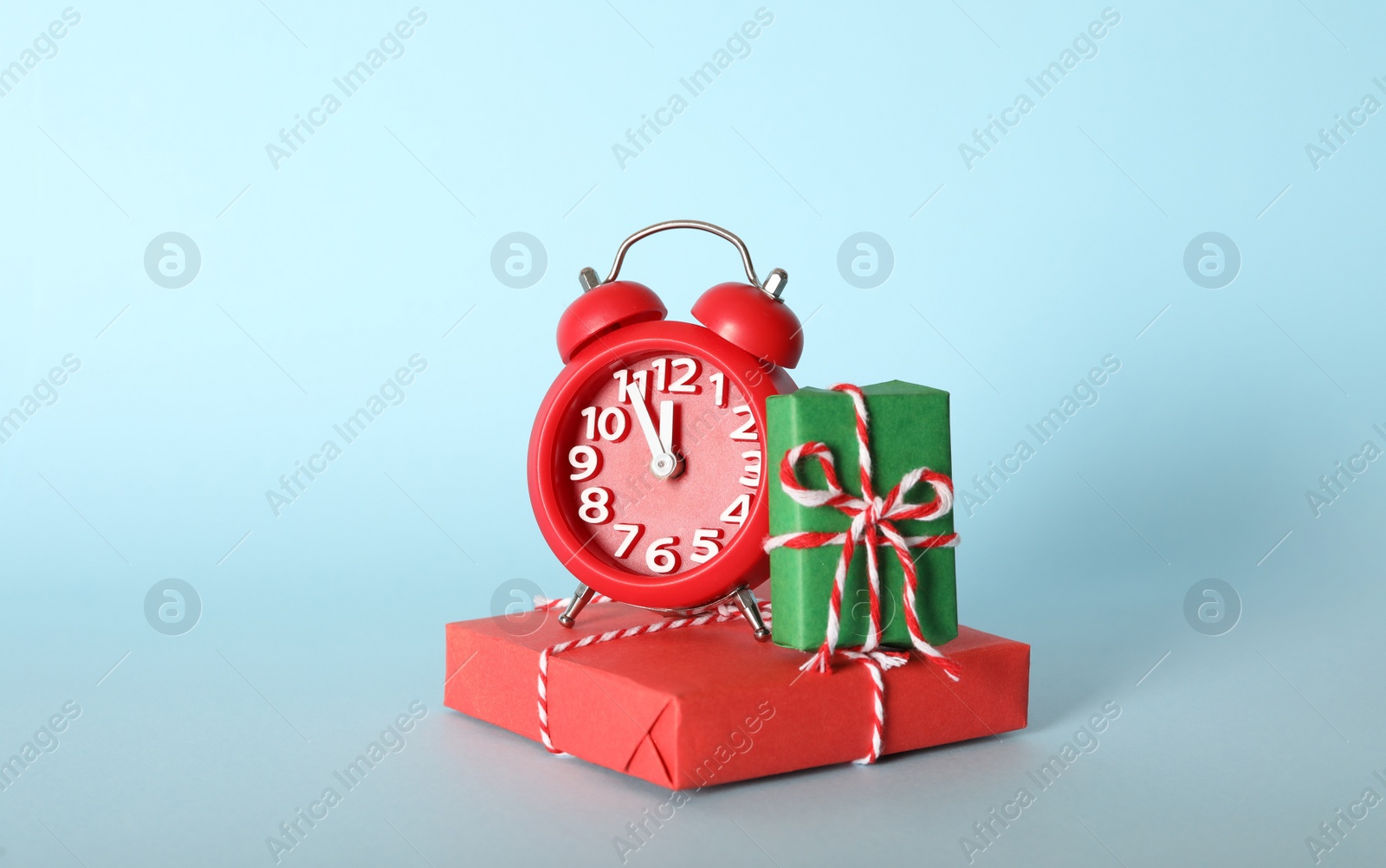 Photo of Alarm clock with Christmas decor on light blue background. New Year countdown