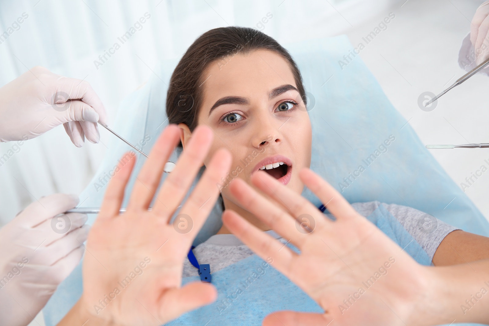 Photo of Young woman scared of dental examination in clinic